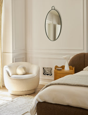 Fern scalloped back boucle upholstered swivel chair styled in a corner of a bedroom