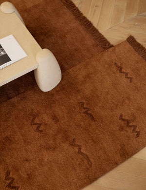Koukero irregular shaped fringe wool area rug styled under a coffee table