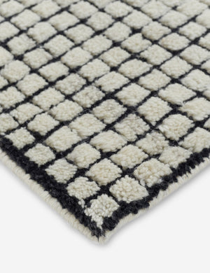 Corner shot of the Uma black and natural checkered grid pattern rug