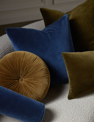 Charlotte velvet pillow in olive and true blue sit on a cream boucle lounger with other velvet pillows