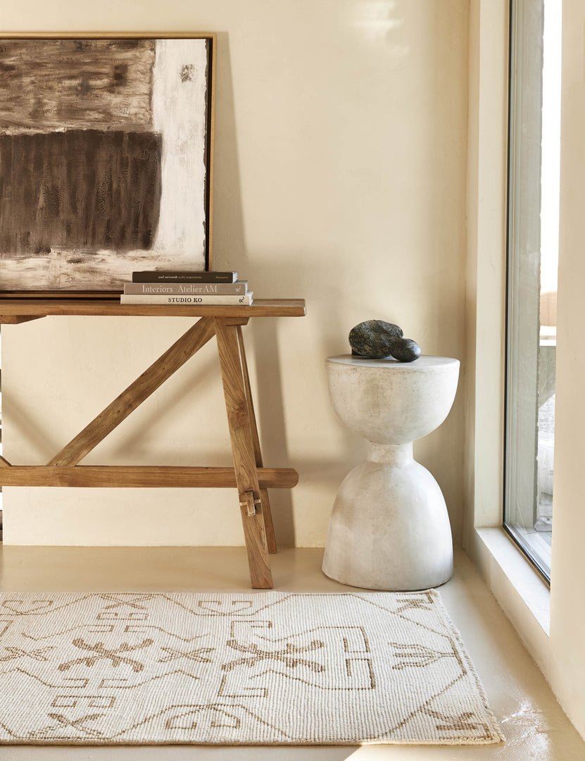 #size::3--x-5- #size::5--x-8- #size::6--x-9- | The Evet neutral geometric wool floor rug lays in a bright entryway in front of a wooden craftsman console table and round stone side table.