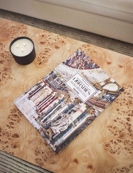 | A photography book and lit candle sit on top of the Brisa rectangular burl wood coffee table with four legs