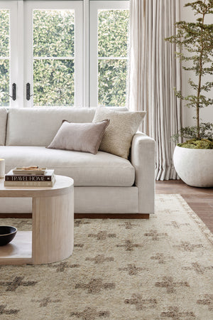 The acoma rug lays in a living room under a gray linen sofa and an oval whitewashed coffee table