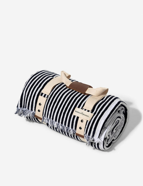 #color::navy-stripe | The Navy and white striped cotton beach blanket by business and pleasure co wrapped up in the leather-handled strap