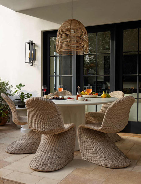 #color::natural | The Beehive jute woven pendant light is hung in a patio over a circular dining table that is surrounded by woven chairs