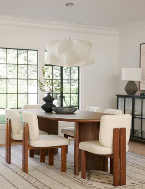 Six Sydney Dining Chairs sit around an oval dining table with a black centerpiece vase beneath a geometric white chandelier