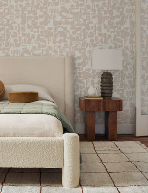 Ivory and taupe Organic Shapes Wallpaper by Sarah Sherman Samuel is in a bedroom with a boucle framed bed, a natural area rug, and a wooden nightstand