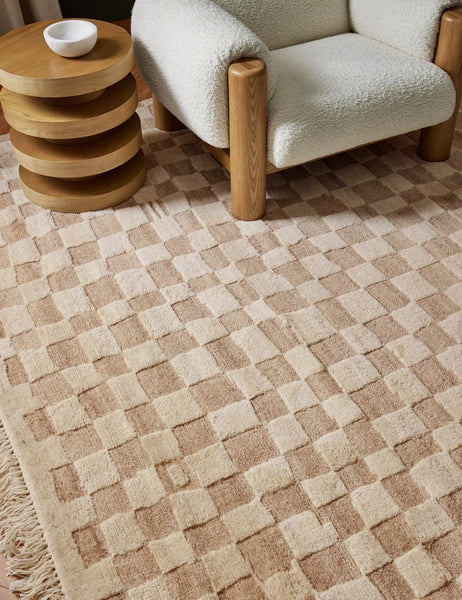 #color::natural #size::2-6--x-8- #size::6--x-9- #size::8--x-10- #size::9--x-12- #size::10--x-14- #size::12--x-15- | The Irregular Checkerboard Rug by Sarah Sherman Samuel sits in a living room with a retro wooden four tiered side table and a white boucle rounded accent chair.