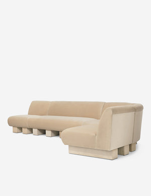 Angled view of the Lena right-facing beige velvet sectional sofa with upholstered beam legs