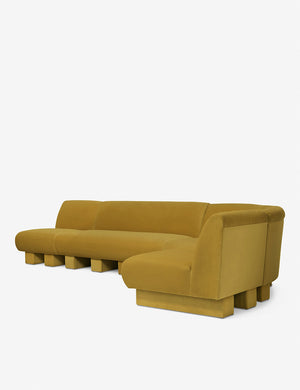 Angled view of the Lena right-facing yellow velvet sectional sofa with upholstered beam legs.