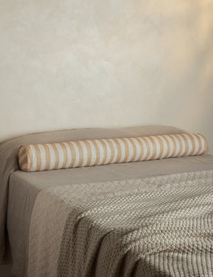 Painterly stripe linen long bolster throw pillow in natural and ivory styled on a bed