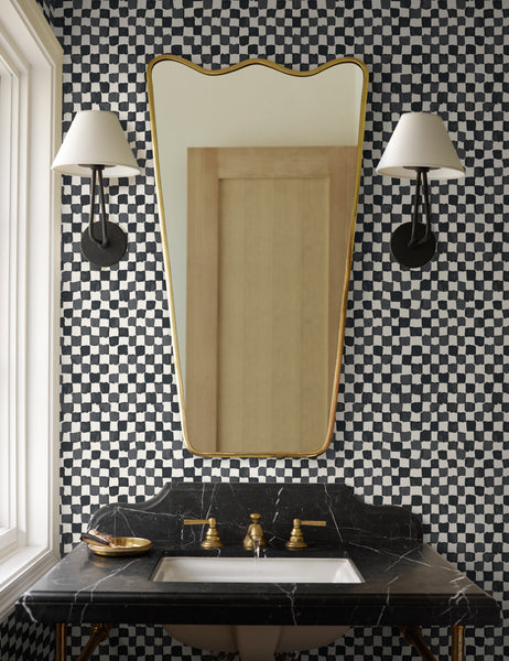 #size::1-light #color::black | Two Hayden double-armed black sconce lights hang on a checkerboard wall in a bathroom next to a gold framed mirror