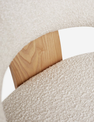 Close-up of the wood-panel back support and white boucle fabric on the wishbone frame of the Celeste honey wood accent chair