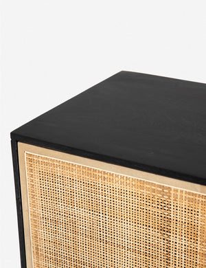 Detailed view of the upper corner of the Hannah black mango wood sideboard with  cane doors and an iron base.