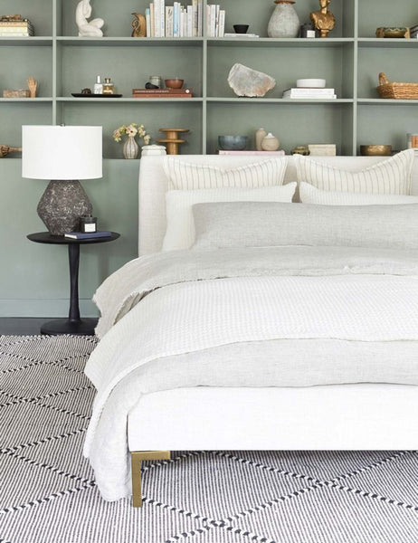 #color::talc-linen #size::twin #size::full #size::queen #size::king #size::cal-king | The Deva Talc Linen platform bed lays in a bedroom with a green inset shelf atop a black and white rug