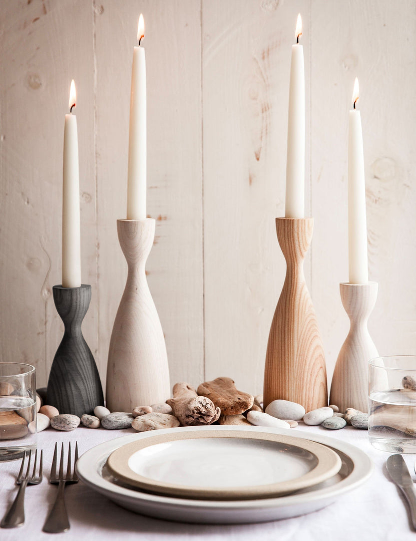 #size::small #size::medium #color::natural #color::grey #color::white | The Pantry wooden candlesticks with smooth curves by farmhouse pottery in gray, neutral, and white sit on a dining room table with neutral dinnerware