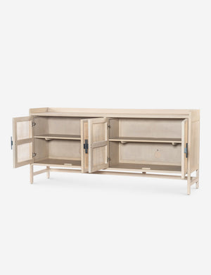 Angled view of the Philene natural mango wood sideboard with cane doors with all four doors open, revealing the inner shelving