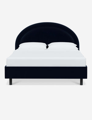 Odele navy Velvet upholstered bed with an arched headboard that has a welted border