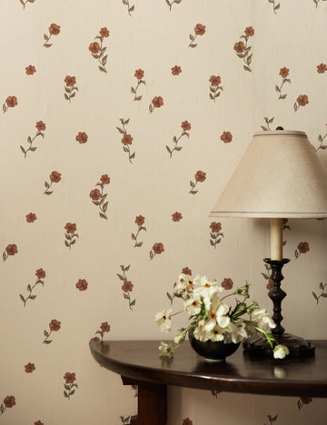 #color::red | A console table with a table lamp sits in front of a wall covered with the Bamonte Textile String Floral Wallpaper by Jake Arnold