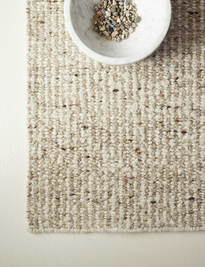 A marble bowl holding river rocks sits on the Taos neutral light brown wool blend area rug.