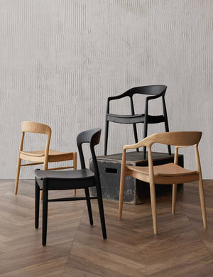 Two Natural and Two Black Ida Dining Arm Chairs sit in a room with a black wooden box, a textured wall, and chevron wooden floors