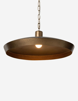 Kamlyn shallow hammered metal dome pendant light in brass with light on.