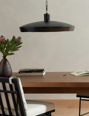 Kamlyn shallow hammered metal dome pendant light in bronze hanging above a table.