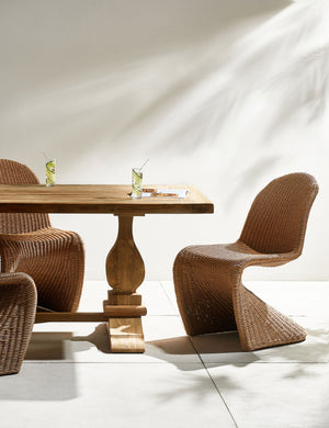Oveido reclaimed teak outdoor dining table styled with rattan outdoor dining chairs.