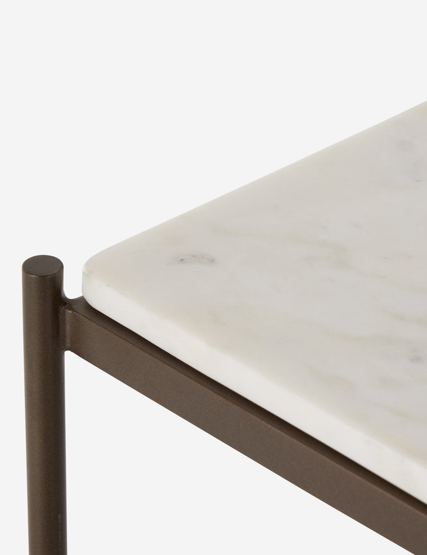 #color::antique-brass | Close up view of the top corner of the Evander brass frame and white marble console table.