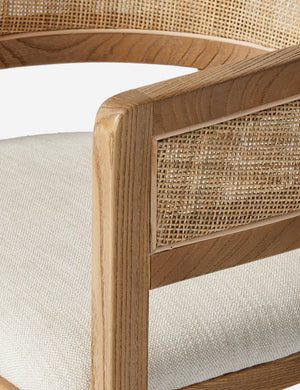 Close up view of the arm of the Kairi light wood cane barrel back dining chair.