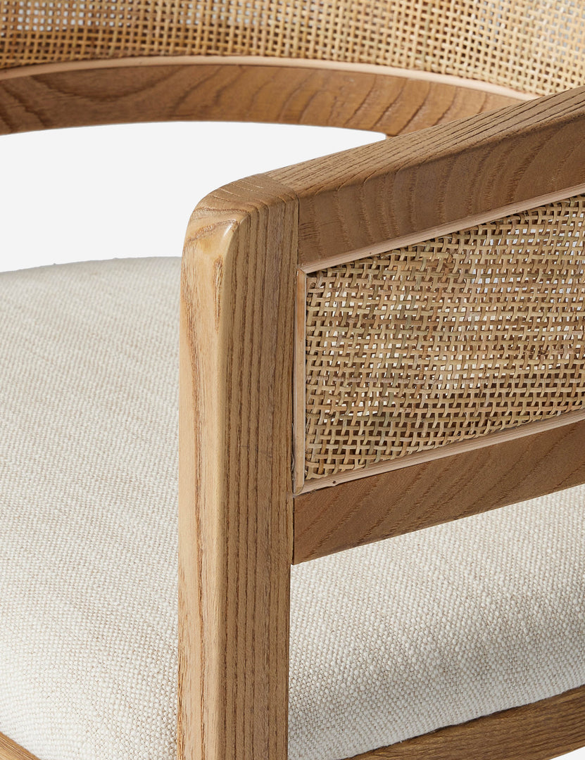 #color::natural | Close up view of the arm of the Kairi light wood cane barrel back dining chair.