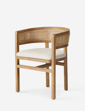 Angled view of the Kairi light wood cane barrel back dining chair.