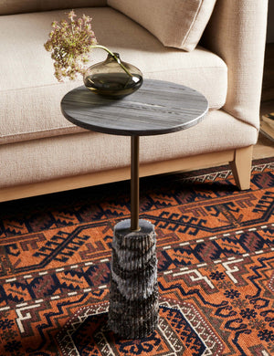 Fallow round marble side table styled with a cream colored sofa and bold orange geometric print rug.