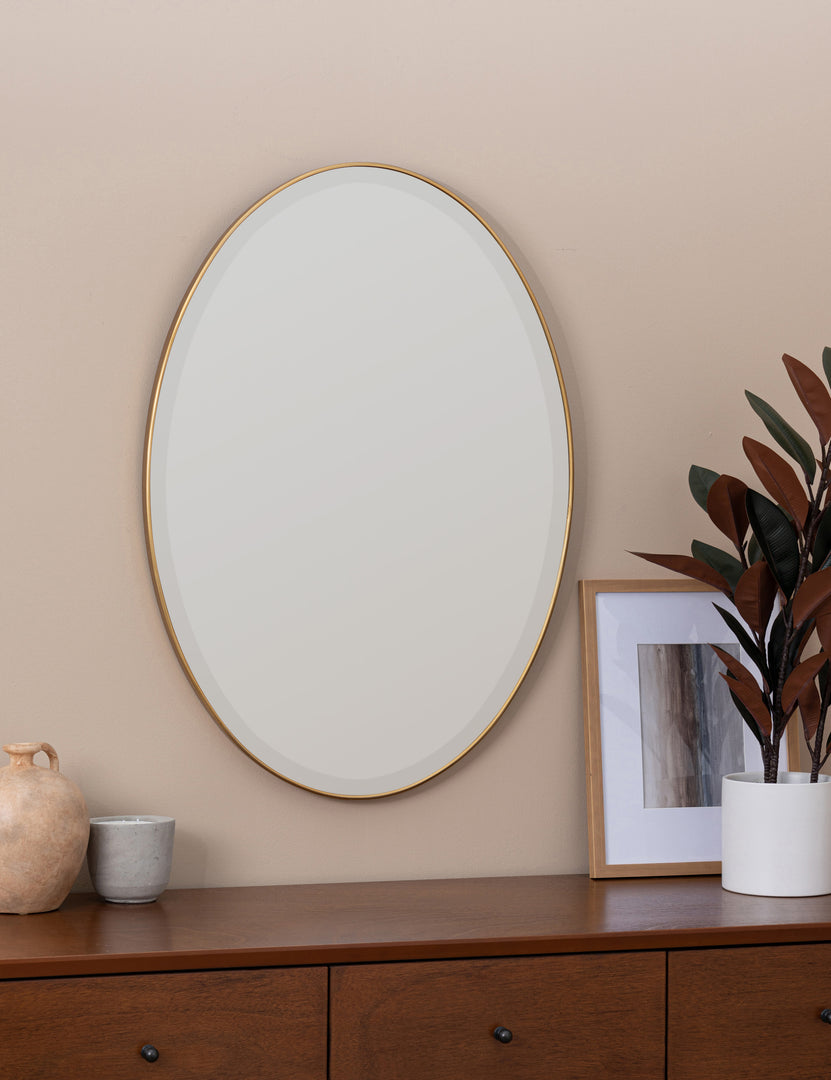 #color::gold | Luke golden oval mirror hangs above a wooden sideboard on a beige-toned wall