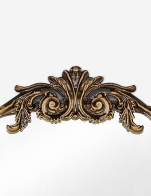 Detailed view of the traditional scroll detailing on the top of the Tulca arched gold mirror with flat bottom edge.