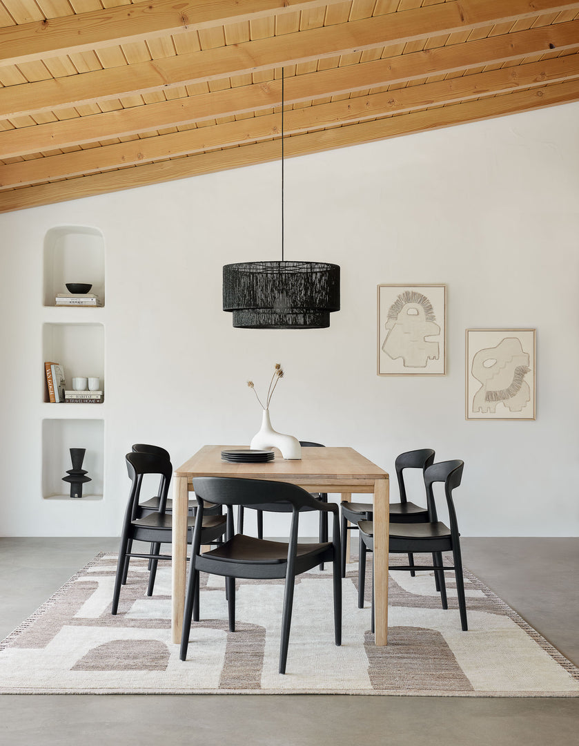 Dining room setting with Elan Byrd rug under a wood dining table with 5 black armless chairs