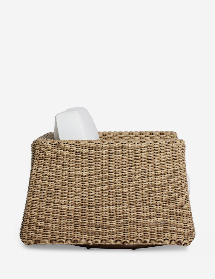 #color::natural | Side profile of the Aisha wide arm modern wicker outdoor swivel chair.