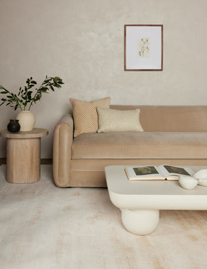 The ivory dylan rug sits in a living room under a white rounded coffee table, a beige velvet sofa, and a round wooden side table
