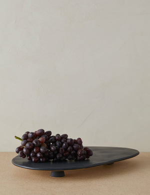 Footed serving display tray in black holding a bunch of grapes