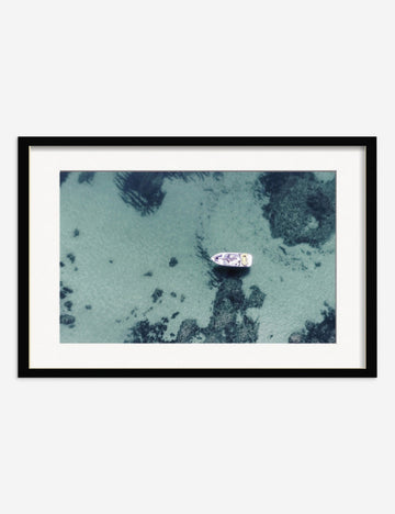 #frame-option::framed #color::black #size::25.5--x-17.5- #size::35.5--x-23.5- #size::45.5--x-29.5- | Aerial Ocean Bliss Photography Print in a black frame featuring an aerial view of a boat on shallow waters by Ingrid Beddoes