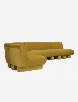 Angled view of the Lena left-facing yellow velvet sectional sofa with upholstered beam legs.