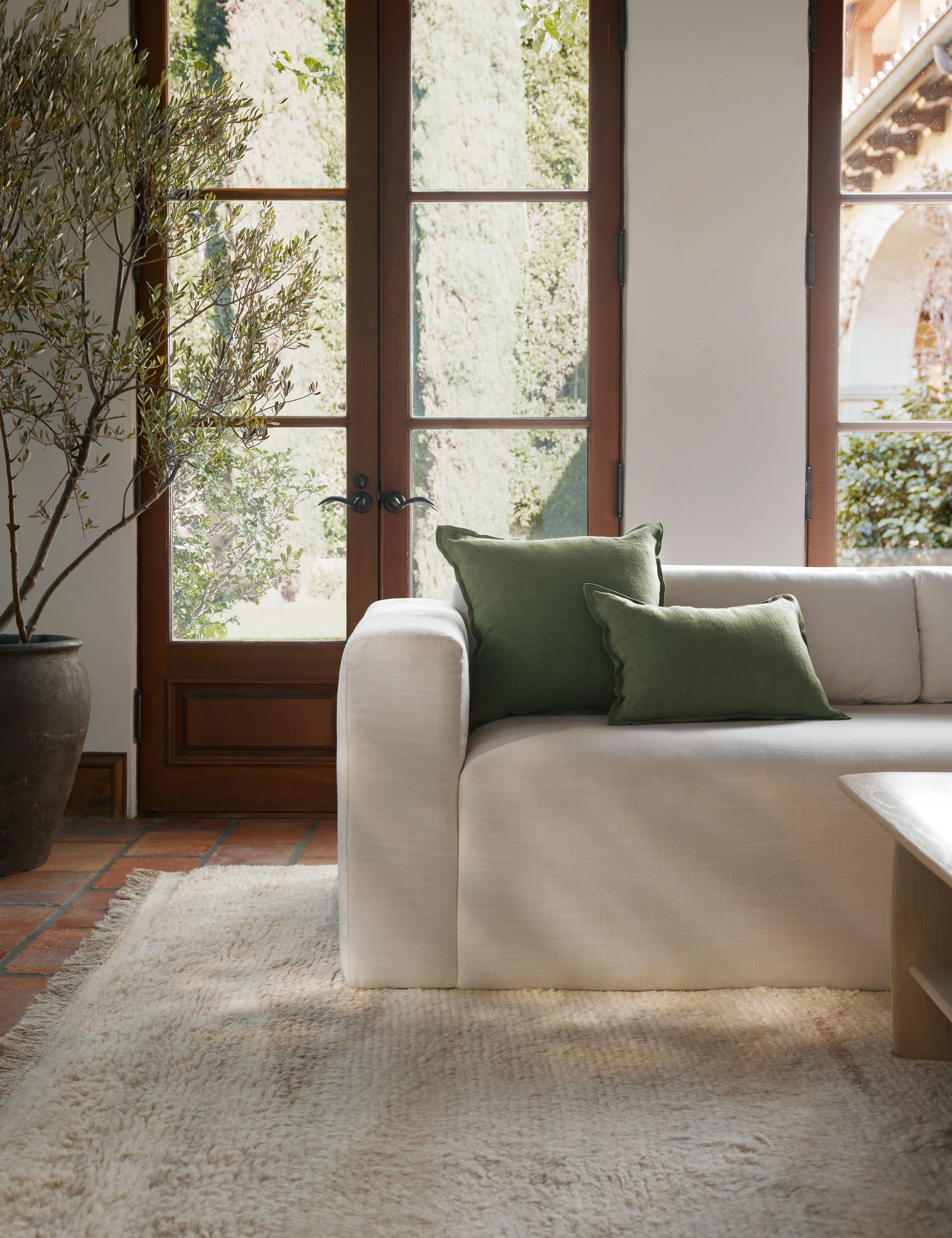 #color::olive #size::lumbar #fill type::with-feather-down-insert #fill type::pillow-cover-only | The arlo Olive green flax linen pillow in its lumber and square sizes sit together on a natural linen sofa