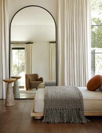 #color::black | Idris thin metal framed floor length mirror in black styled next to a table and daybed