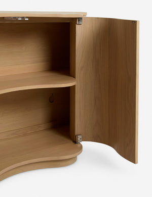 Close up of the Cora half-moon, wavy light-wood sideboard with open door