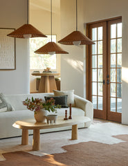 #color::natural #size::25-dia | Three of the Terrene Woven Rattan Pendant by Elan Byrd hanging above a coffee table.