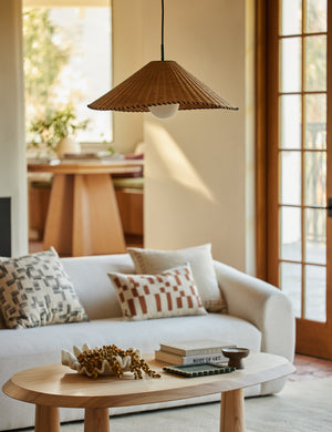 Terrene Woven Rattan Pendant by Elan Byrd hanging above a coffee table.