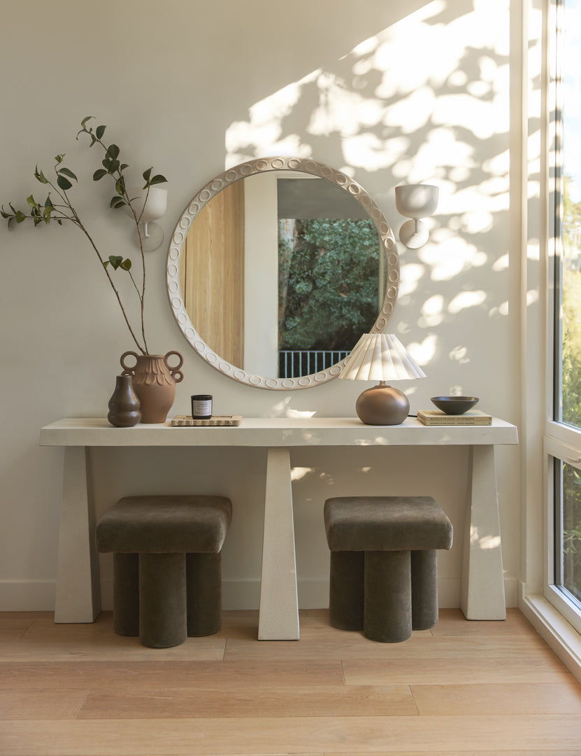 #color::textured-white | A round wall mirror hangs above the Avila modern narrow console table.