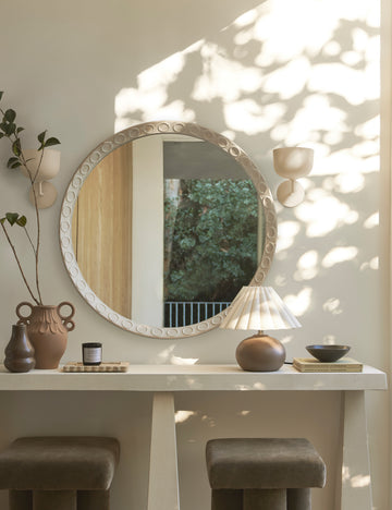 #color::sand | Two Talley modern sculptural wall sconces hung beside an oval mirror above a console table.