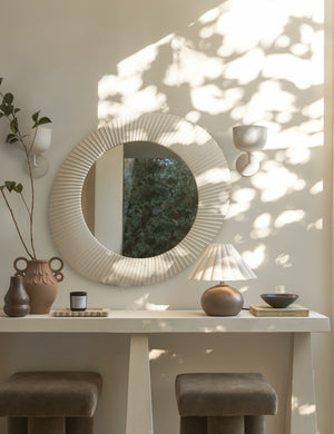 Two Talley modern sculptural wall sconces hung beside an oval mirror above a console table.
