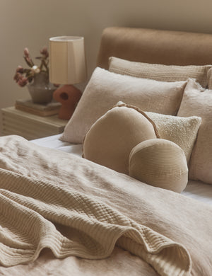 Arlo linen flange trim round pillow styled with other pillows on a bed.